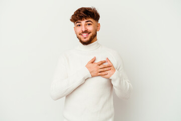 Young Moroccan man isolated on white background has friendly expression, pressing palm to chest. Love concept.