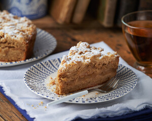 Piece of Apple streusel Crumble Cake pie with crumbles and tea on wooden background. 