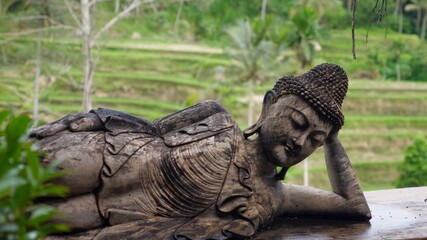 Balinese traditional sculptures. Buddha figure laying leaning on its hand