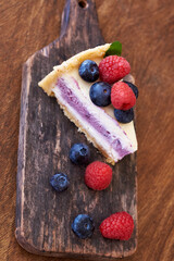 Cheesecake with berries on a wooden background. Side view.