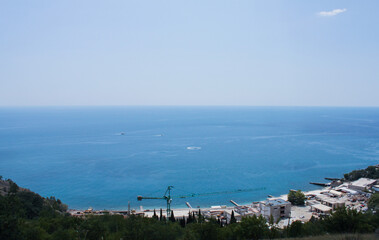 Top view of a construction site with a crane and unfinished concrete structures near the sea on the shore in the bay