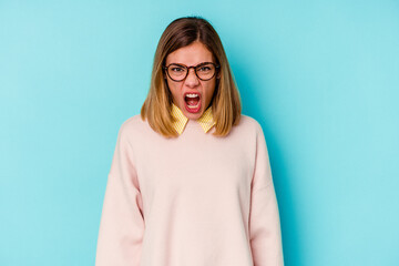 Young student caucasian woman isolated on blue background screaming very angry and aggressive.