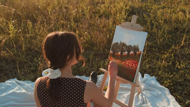 Giovane ragazza italiana dipinge il quadro in un prato di pomeriggio