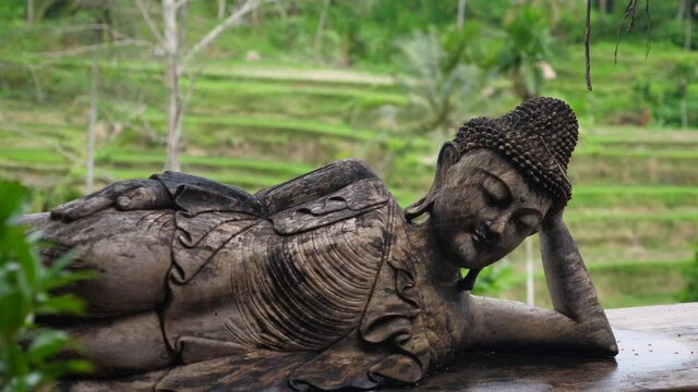 Balinese traditional sculptures. Buddha figure laying leaning on its hand
