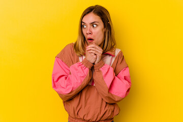 Young caucasian skinny woman isolated on yellow background praying for luck, amazed and opening mouth looking to front.