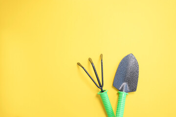 shovel and rake on a yellow background. backyard vegetable garden planting concept with copy space....