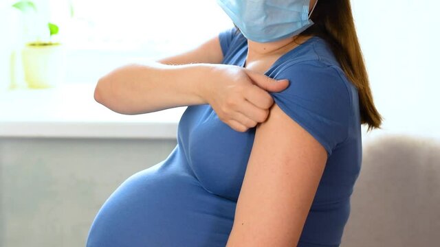 Pregnant Woman in blue protective mask getting ready to be vaccinated in Clinic. Covid-19, Corona Virus vaccination campaign. Pregnant Vaccination. Covid-19 and Flu Vaccine. Protection of Pregnancy.