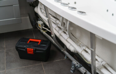 Toolbox near pipe system of bathtub with hydromassage.