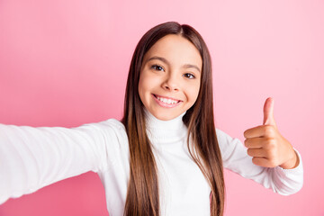 Photo of adorable sweet schoolgirl dressed white sweater recording video showing thumb up isolated pink color background