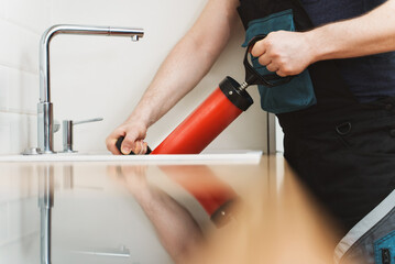 Plumber unclogging kitchen sink with professional force pump cleaner.