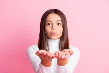 Photo of pretty little girl hands palms send air kiss camera isolated on pastel pink color...