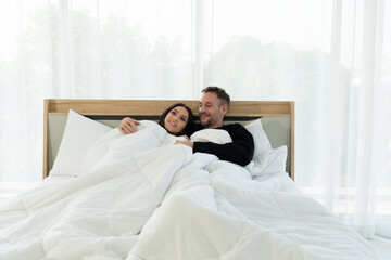 Fototapeta premium happy caucasian couple lying in the bed in bedroom at home in the morning