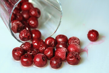 Frozen cherry in the glass on white surface, selective focus