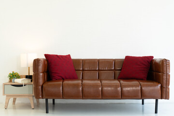 beautiful brown couch with red sham and small table decorate in white living room. interior design concept