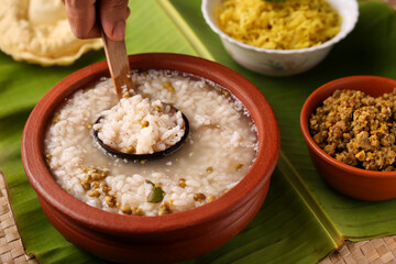 Rice porridge, Kanji, gruel in clay pot palm mat background Kerala South India.  congee, rice soup,...