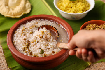 Rice porridge, Kanji, gruel in clay pot palm mat background Kerala South India. congee, rice soup, green gram curry, chammanthi. Ayurveda diet for immunity. porridge Indian Sri lankan veg food.