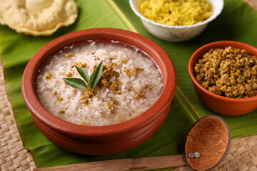 Rice porridge, Kanji, gruel in clay pot palm mat background Kerala South India. congee, rice soup, green gram curry, chammanthi. Ayurveda diet for immunity. porridge Indian Sri lankan veg food.