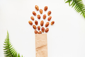 Explosion of creative food: dates from paper package close up on white background. Creative concept of proper snacks