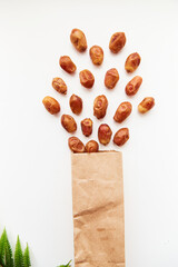 Explosion of creative food: dates from paper package close up on white background. Creative concept of proper snacks