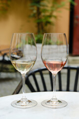 Two glasses of white and rose wine on a table in a restaurant. Summer holiday. Celebrate and enjoy moment. Alcoholic drink tasting. Romantic evening aperitif. Wine glass close up