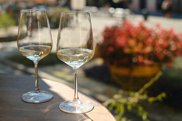 Two glasses of white wine in the sun on a table in a restaurant. Summer holiday. Celebrate and enjoy moment. Alcoholic drink tasting. Romantic evening aperitif. Wine glass close up