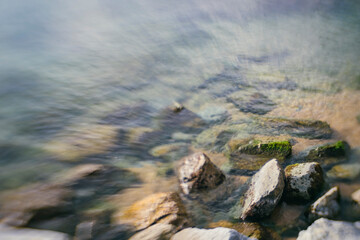 Fototapeta na wymiar Shore rocks landscape on quiet blurry sea waters seascape