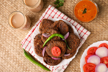Many beef or chicken cutlet, tomato sauce Kerala South India. hot and spicy tea time snack on white plate, dark black background. fried meat of veal, mutton or fish. Top view Indian snack non veg food