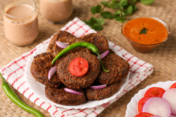 Many beef or chicken cutlet, tomato sauce Kerala South India. hot and spicy tea time snack on white plate, dark black background. fried meat of veal, mutton or fish. Top view Indian snack non veg food