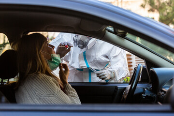 Medical worker in PPE performing drive-thru COVID-19 test