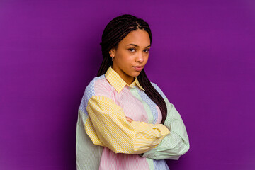 Young african american woman isolated on yellow background frowning face in displeasure, keeps arms...