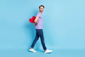 Full body profile photo of positive person hands hold paper heart card behind back isolated on blue color background