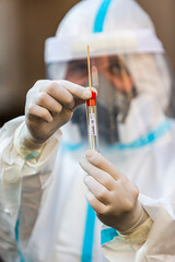 Medical worker in PPE holding COVID-19 test