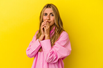 Young blonde caucasian woman isolated on yellow background scared and afraid.