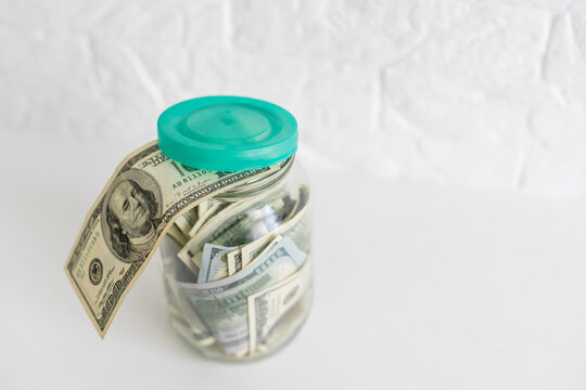 Folding money in a jar on a white wooden background. The background image place for text.