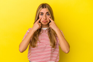 Young blonde caucasian woman isolated on yellow background crying, unhappy with something, agony and confusion concept.