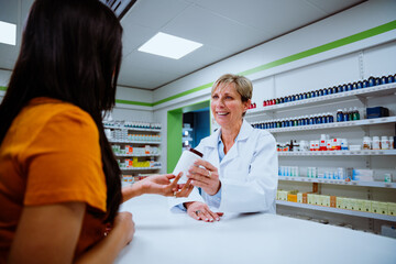 Mixed race patient purchasing medication form caucasian pharmacist standing over the counter in drugstore