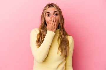 Young blonde caucasian woman isolated on pink background shocked, covering mouth with hands, anxious to discover something new.