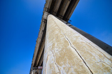 bottom view of man jumping from high bridge on sky background at sunny day 
