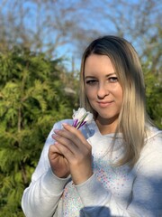 A young and happy blonde woman is holding a bouquet of flowers in her hands. Crocus bouquet.