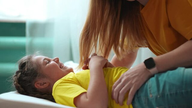 mother tickle daughter. happy family a playing on the bed at home. happy family home kid dream concept. mom tickles daughter play laugh fun. mom tickle daughter lying lifestyle on the bed