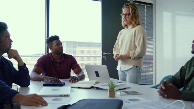 Passionate caucasian businesswoman giving presentation in front of diverse colleagues in board room