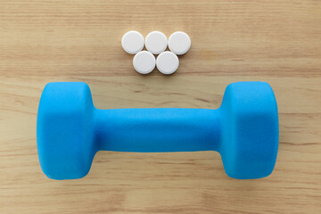 Five round tablets symbolizing medicines or stimulants. Blue dumbbell symbolizing sports, fitness.