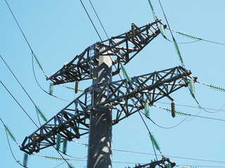 Fragment of a pillar with many electrical wires against a blue sky. Power lines
