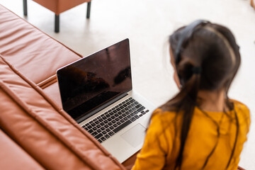 Smart Little Girl Does Homework in Her Living Room. She's Sitting and Uses Laptop.