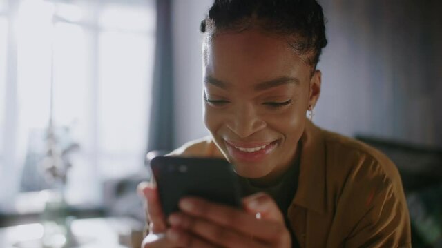 Pretty optimistic african american woman using smartphone social media apps laughing of fun video concent searching internet communcating. Home lifestyle.