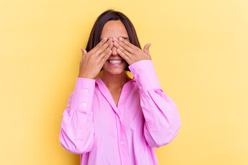 Young mixed race woman isolated on yellow background covers eyes with hands, smiles broadly waiting for a surprise.