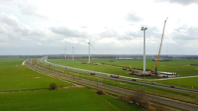 Construction of a new wind park with a row of large windturbines and a passing train near the Hattemerbroek junction next to the N50 highway in Gelderland, The Netherlands.