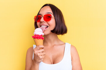 Young mixed race woman holding an ice cream isolated on yellow background