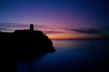 sunrise over a silhouette of Ha lighthouse in Aberdour, fife,  scotland.