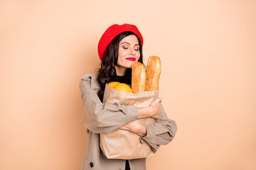 Photo of calm charming lady hold bag bread smell fresh pastry isolated on pastel beige color background